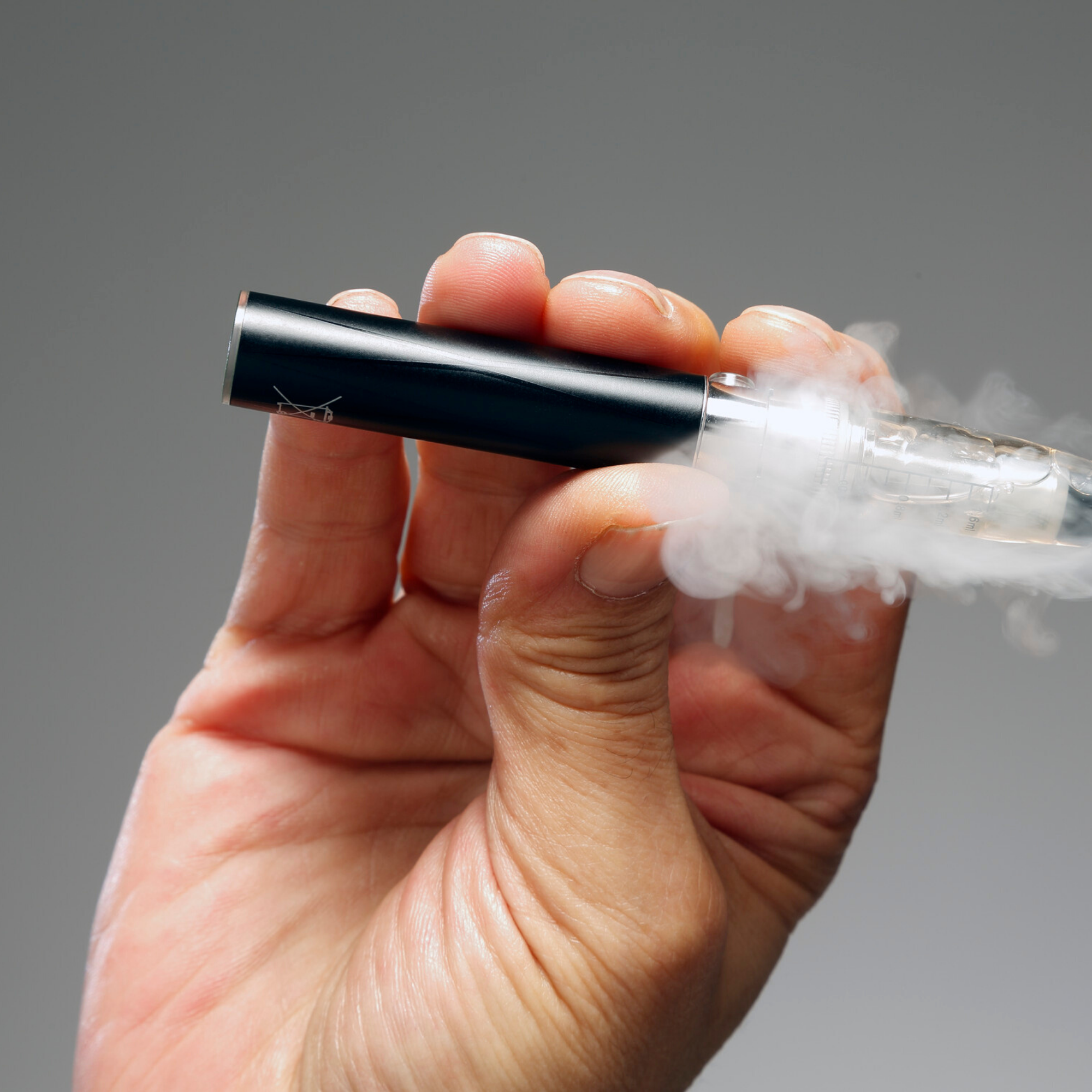 Man holding a vape, highlighting the risk of vaping and the risk to your oral health.