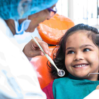 Child smiling at an orthodontist during her first visit to keep an eye on how her teeth are moving and developing.