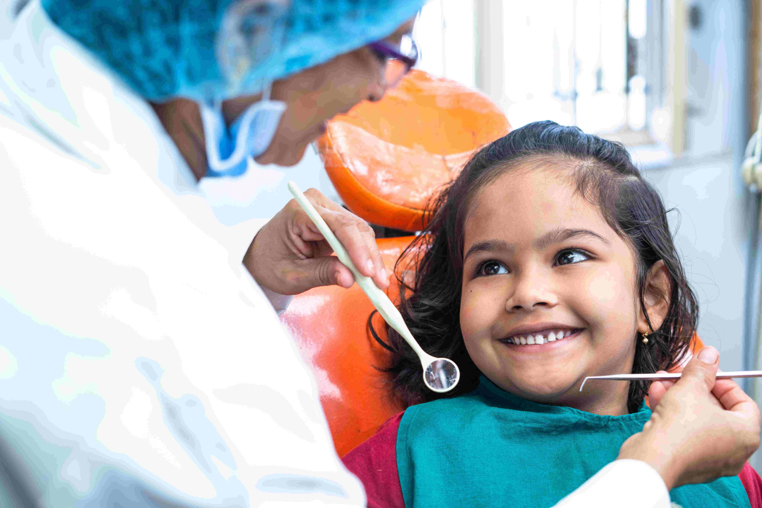 Child smiling at an orthodontist during her first visit to keep an eye on how her teeth are moving and developing.