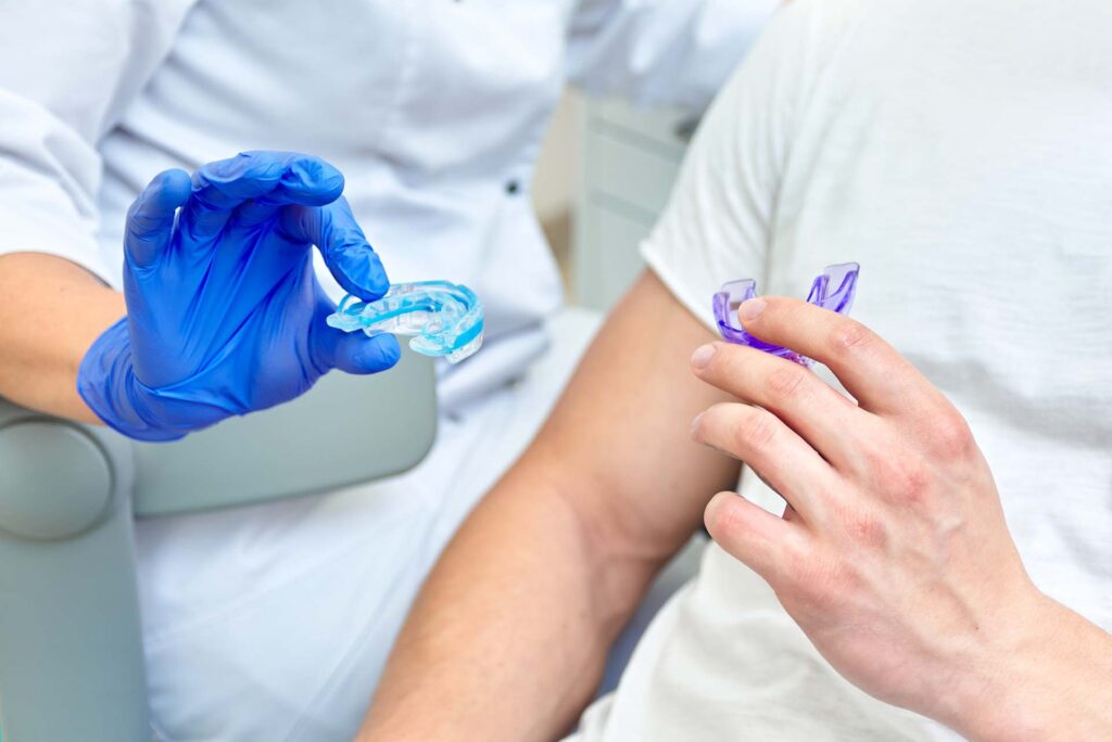 An AAO Orthodontist discussing with a patient the correct mouthguard to use to protect their teeth and braces. 