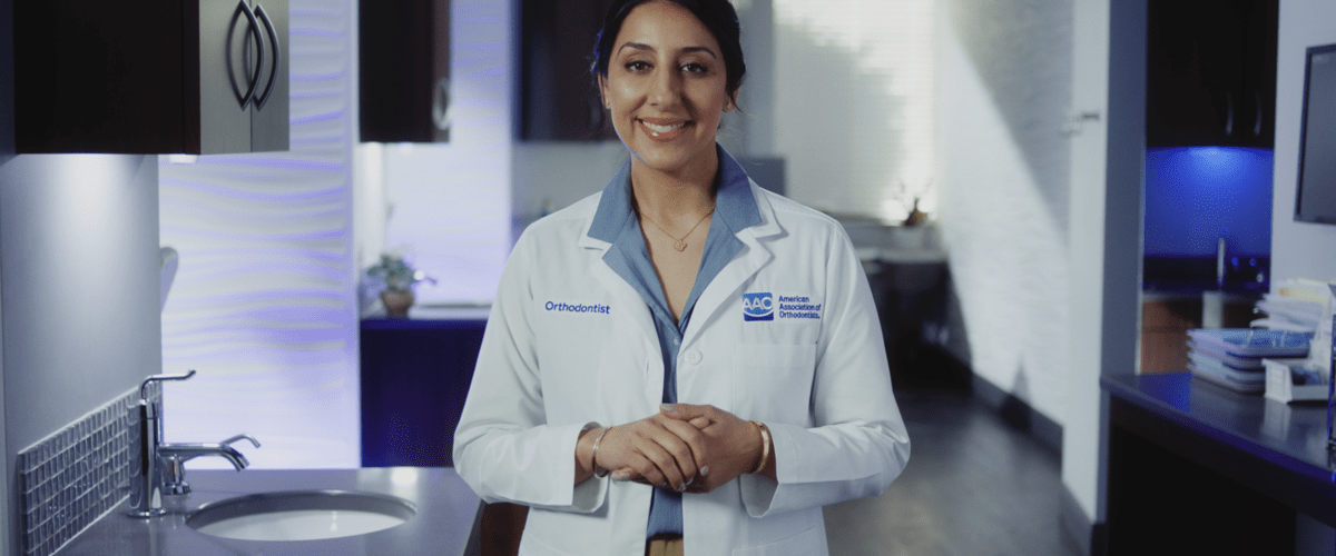 An Orthodontist standing in a hallway, ready to discuss what to expect at your first orthodontic appointment.