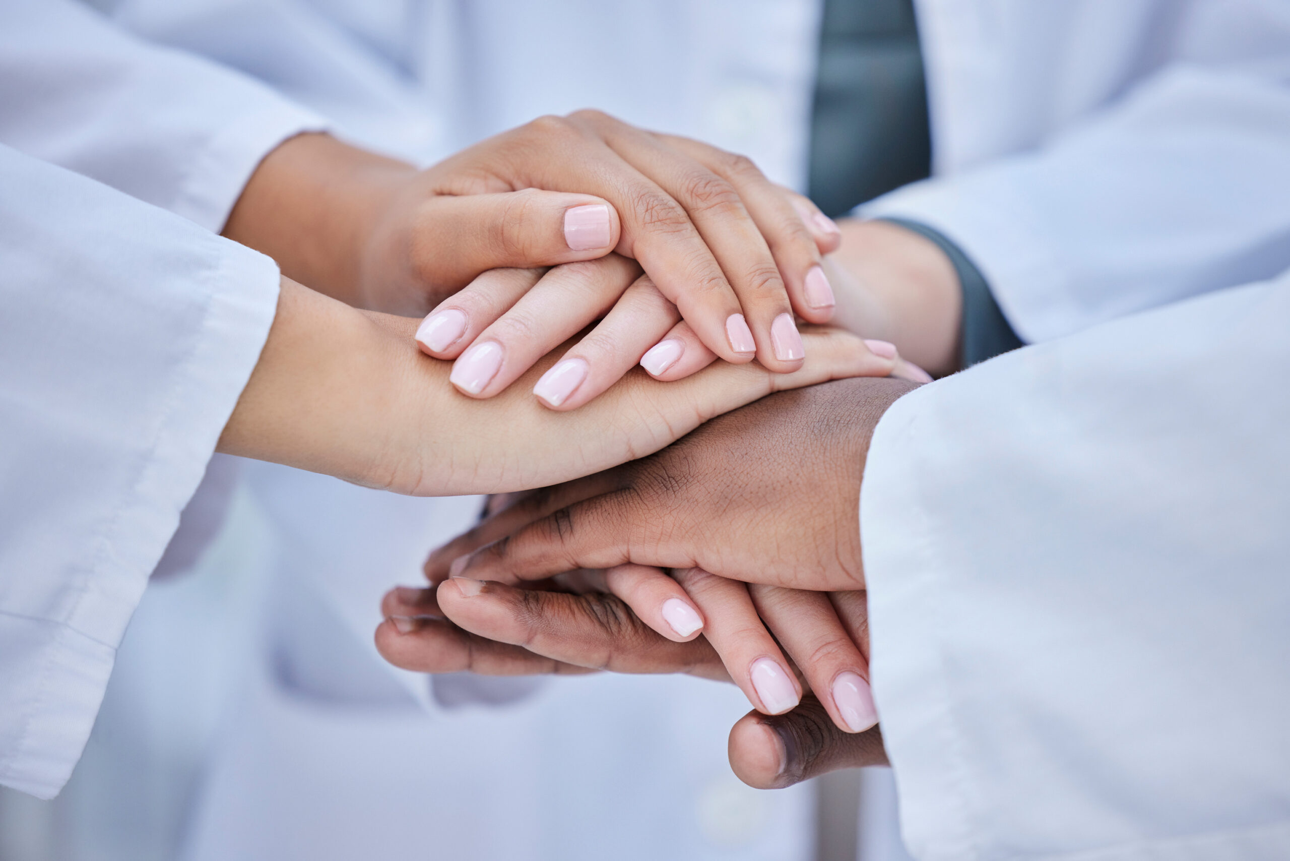 Image of orthodontists hands stacked on top of one another to show support to patients of mail-order treatment.