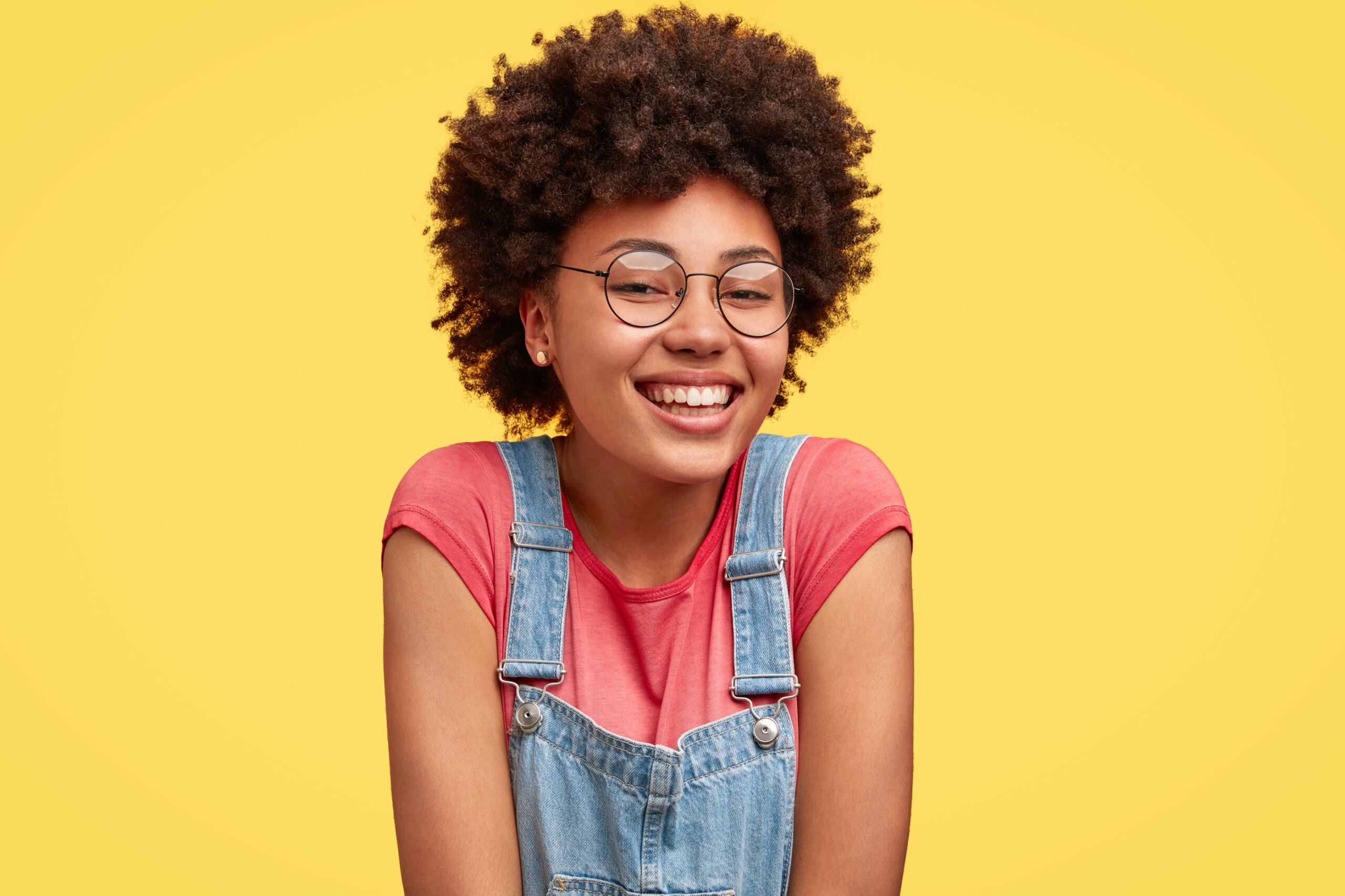 Young girl smiling with her shoulders shrugged.