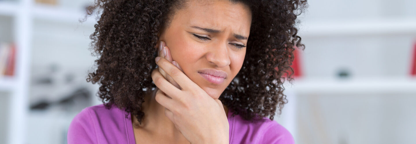 Woman in visible pain with dental issues, and it's time to see an AAO orthodontist.