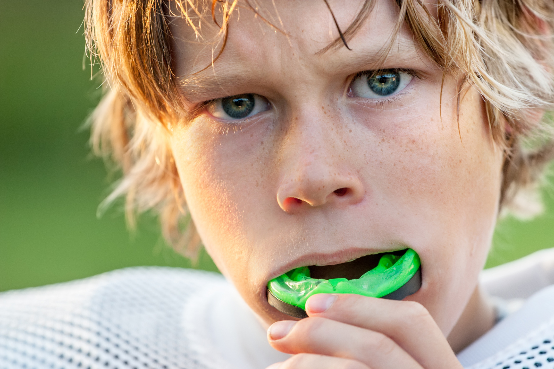 Teenage boy putting in a mouth guard, while playing football.